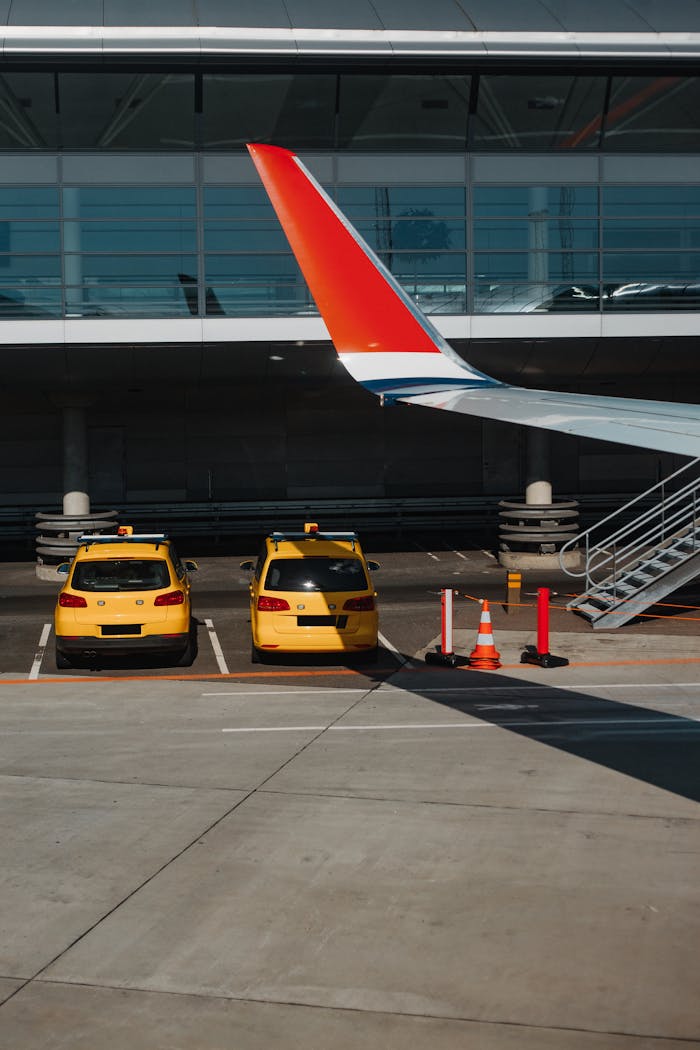 why-choose-us-02 Two yellow taxis parked under an airplane wing at an urban airport.